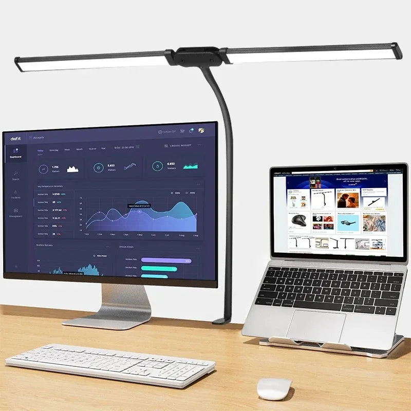 Desk setup with computer monitor, laptop, keyboard, and mouse under a flexible LED desk lamp.